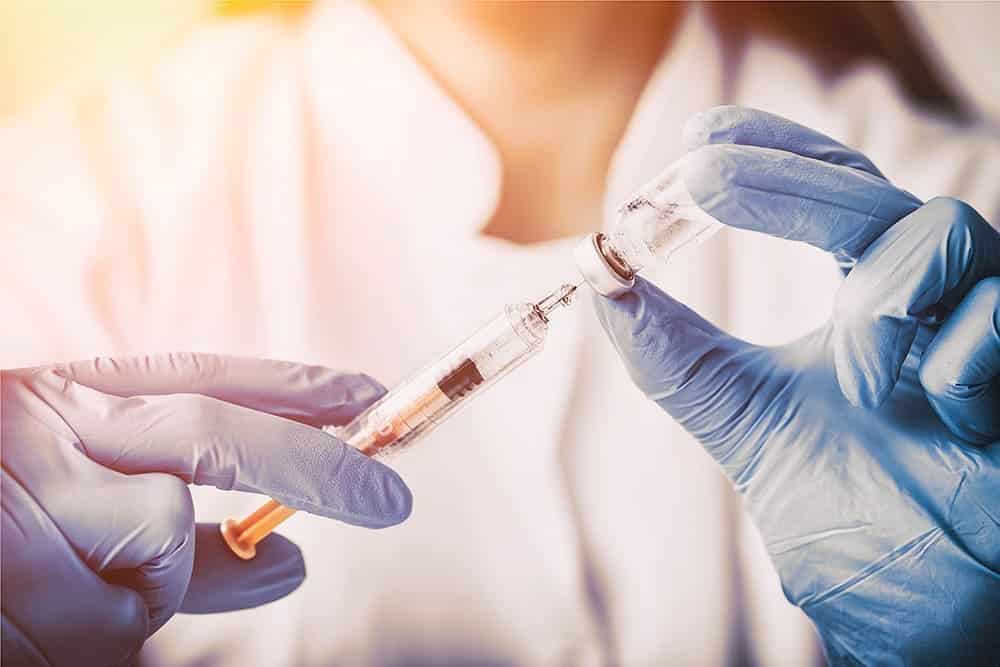 Pessoa com luvas preparando uma vacina