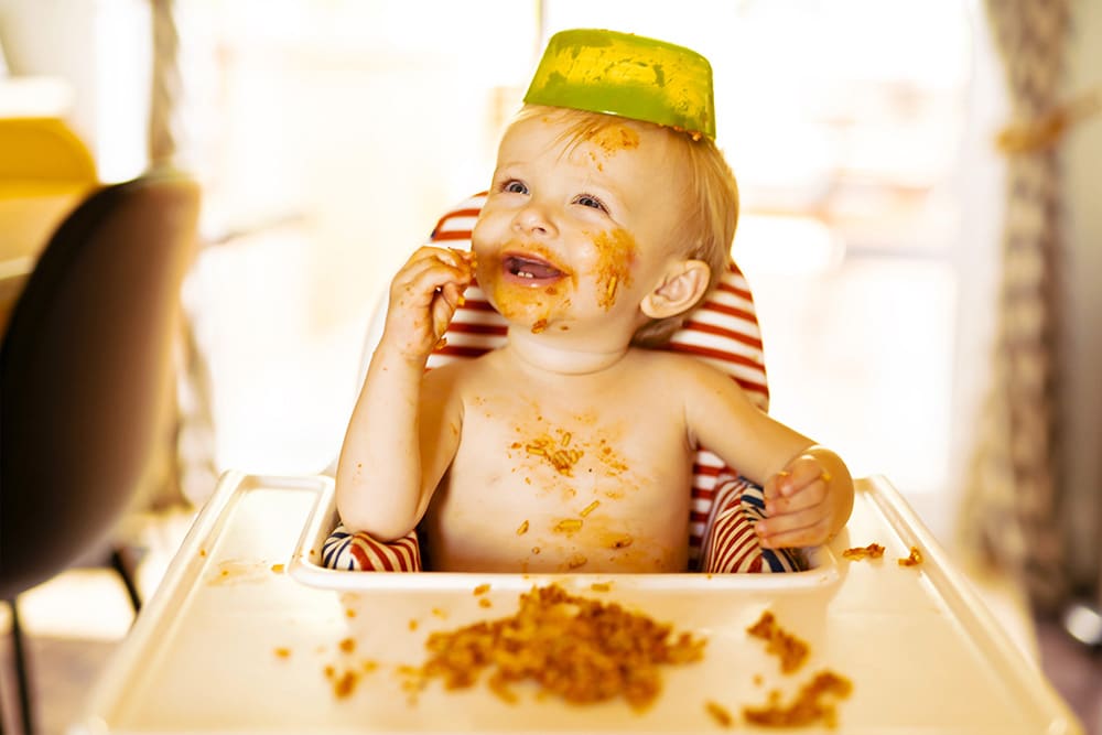 criança feliz sentada comendo
