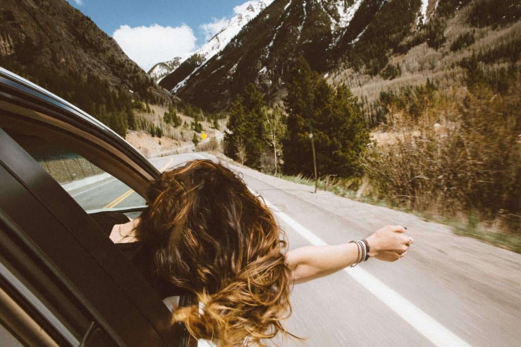Mulher viajando sozinha de carro, andando pela estrada.